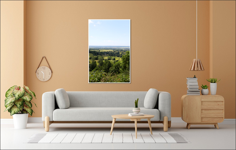 Salon contemporain aux tons orange et beige avec canap� en tissu, plante verte et commode design, d�cor� d�une photo verdoyante du panorama sur la vall�e de la Dives � Mont-Ormel, bocage normand et lieu de m�moire de 1944